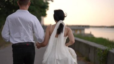 Zarif beyaz elbiseli gelin ve beyaz gömlekli damat nehir kenarında el ele yürüyorlar. Ağır çekimde yakalanan sahne aşkı, birlikteliği ve paylaşılan bir hayatın başlangıcını yansıtıyor..