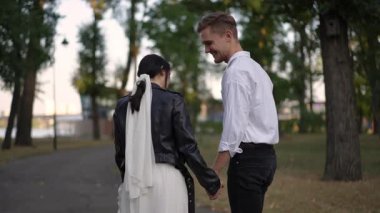 Modern bir çift, zarif giyinmiş ve neşeli bir şekilde birbirine bağlanmış, açık havada güzel bir anın tadını çıkarıyor.