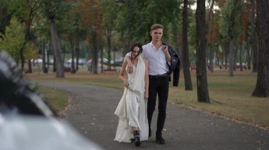 Bir çift el ele yürür, huzurlu ve huzurlu bir parkta güzel ve canlı bir sonbahar gününün tadını çıkarırlar.