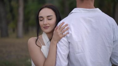 Gelin elini nazikçe damat omuzunda nişan yüzüğü ve elmasla dinlendiriyor. Düğün gününün zarafetini ve samimiyetini gösteriyor..