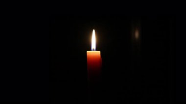 Karanlık bir ortamın içindeki sıcak ve davetkar parıltıyı vurgulayan büyüleyici bir mum serisi.