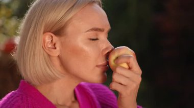 Açık havada otururken taze elmanın tadını çıkaran ve tadını çıkaran bir insan.