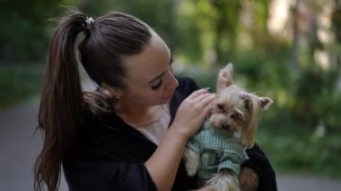 Bir kadın, güzel bir açık havada küçük köpeğiyle sevgi dolu ve sevgi dolu anları paylaşmaktan hoşlanır.