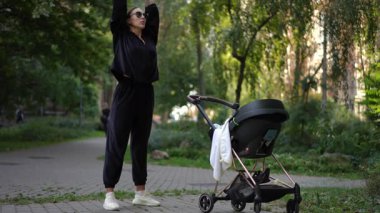 Modaya uygun bir anne, bebek arabasıyla güzel manzaralı bir park ortamında keyifli bir an geçirir.