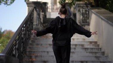 Yeşilliklerle çevrili bir açık hava merdivenine tırmanan bir insan hem hareketini hem de yaşam tarzını yakalar.