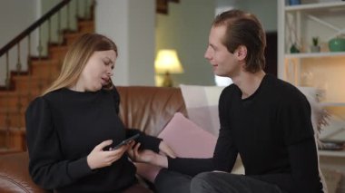 Kocası eline ulaşmaya çalışırken, bir kadın telefonunu tutarak, gözle görülür bir kızgınlıkla arkasını döner. Sahne, evdeki sorunlu ilişkilerinde gerginlik, reddedilme ve duygusal mesafeyi vurguluyor.