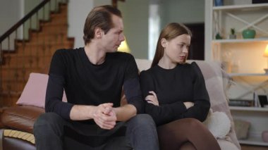 Genç bir çift hararetli bir tartışmadan sonra, her ikisi de göz temasından kaçınarak sessizce kanepede oturur. Kadın kollarını kavuşturup hayal kırıklığıyla yüz çevirirken adam yorgun ve bitkin görünüyor.