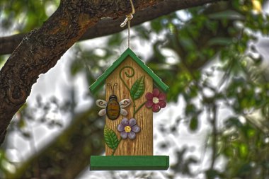 Ağaçta asılı duran küçük ahşap kuş yemi.