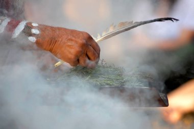 Avustralya 'da bir yerel halk etkinliğinde dumanla yapılan törende insan eli ahşap tabak ve tüy tutulur.