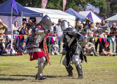 Paracombe, South Australia - 05.05.2024: Medieval Fair, community entertaining event, knights jousting, skill at arms competitions, and battles with knights in armor on horses, medieval adventure. clipart
