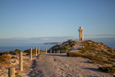 Okyanus kıyısındaki deniz feneri mavi gökyüzünün arka planında, deniz fenerine giden yol, güzel deniz manzarası. Yüksek kalite fotoğraf
