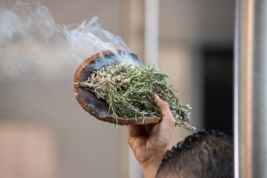 Australian Aboriginal Ceremony, man hand with green branches and flame, start a fire for a ritual rite at community event in South Australia clipart