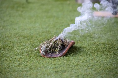 Australian Aboriginal Ceremony, man hand with green branches and flame, start a fire for a ritual rite at community event in South Australia clipart