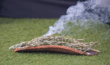 Australian Aboriginal Ceremony, man hand with green branches and flame, start a fire for a ritual rite at community event in South Australia clipart