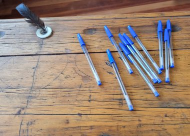 Modern writing pens are scattered on an old wooden student desk. High quality photo clipart