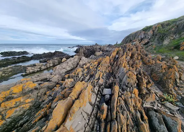 Güney Avustralya 'da okyanus kıyıları, kayalar, alışılmadık kırmızı taşlar. Bulutlar ve çizgiler. Deniz Burnu. 