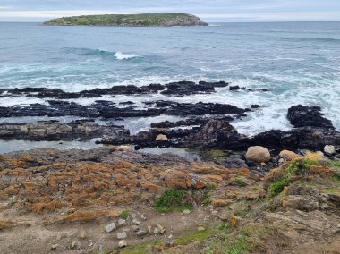 Güney Avustralya 'da okyanus kıyıları, kayalar, alışılmadık siyah taşlar. Bulutlar ve çizgiler. Deniz Burnu. 