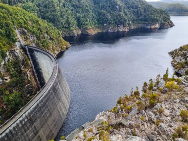 Tazmanya 'daki Gordon Barajı, engebeli uçurumlarla çevrili etkileyici bir beton yapı ve ıssız bir yerde sakin bir göl. Yüksek kalite fotoğraf