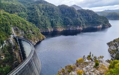 Tazmanya 'daki Gordon Barajı, engebeli uçurumlarla çevrili etkileyici bir beton yapı ve ıssız bir yerde sakin bir göl. Yüksek kalite fotoğraf
