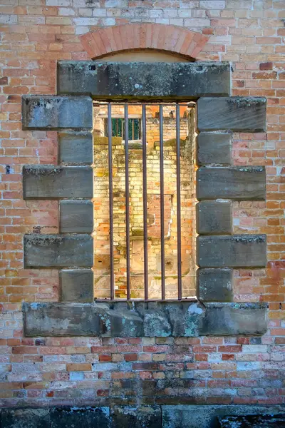 Parmaklıklı pencereli eski tuğla duvar, zamansız bir atmosferde tarihi mimari ve klasik dokular sergiliyor. Yüksek kalite fotoğraf