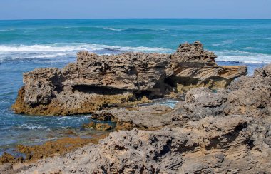 Keskin kıyı kaya oluşumları ve turkuaz okyanus dalgaları Güney Avustralya 'nın engebeli kıyı şeridinde buluşuyor.
