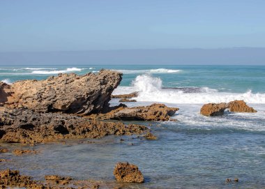Keskin kıyı kaya oluşumları ve turkuaz okyanus dalgaları Güney Avustralya 'nın engebeli kıyı şeridinde buluşuyor.