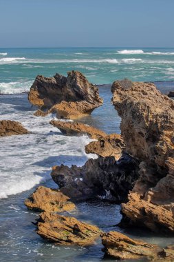 Keskin kıyı kaya oluşumları ve turkuaz okyanus dalgaları Güney Avustralya 'nın engebeli kıyı şeridinde buluşuyor.