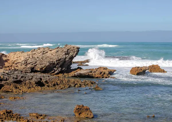 Keskin kıyı kaya oluşumları ve turkuaz okyanus dalgaları Güney Avustralya 'nın engebeli kıyı şeridinde buluşuyor.