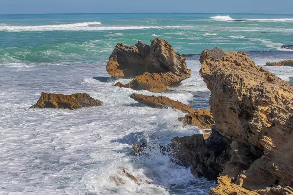 Keskin kıyı kaya oluşumları ve turkuaz okyanus dalgaları Güney Avustralya 'nın engebeli kıyı şeridinde buluşuyor.
