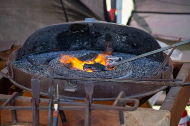 Geleneksel kalpazanlık gösterisi sırasında demircilerin elleri çekiçle örse metal çubuk tutarken yakın plan.