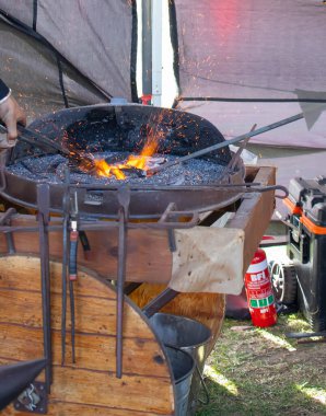 Geleneksel kalpazanlık gösterisi sırasında demircilerin elleri çekiçle örse metal çubuk tutarken yakın plan.