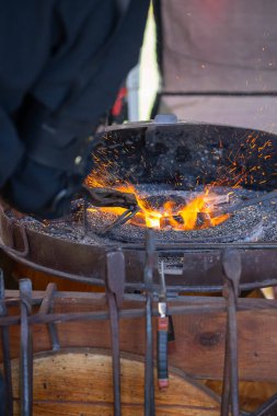 Geleneksel kalpazanlık gösterisi sırasında demircilerin elleri çekiçle örse metal çubuk tutarken yakın plan.