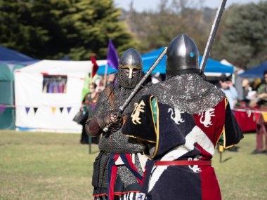 Paracombe, Güney Avustralya 05.03.2025. Güney Avustralya 'daki Ortaçağ Fuarı' nda kılıçlar ve kalkanlarla yapılan yeniden canlandırma turnuvasında zırhlı şövalyeler düello yapıyor.