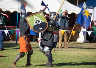 Paracombe, Güney Avustralya 05.03.2025. Güney Avustralya 'daki Ortaçağ Fuarı' nda kılıçlar ve kalkanlarla yapılan yeniden canlandırma turnuvasında zırhlı şövalyeler düello yapıyor.