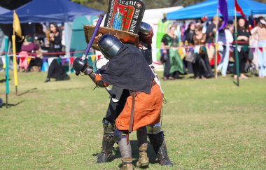 Paracombe, Güney Avustralya 05.03.2025. Güney Avustralya 'daki Ortaçağ Fuarı' nda kılıçlar ve kalkanlarla yapılan yeniden canlandırma turnuvasında zırhlı şövalyeler düello yapıyor.