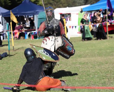 Paracombe, Güney Avustralya 05.03.2025. Güney Avustralya 'daki Ortaçağ Fuarı' nda kılıçlar ve kalkanlarla yapılan yeniden canlandırma turnuvasında zırhlı şövalyeler düello yapıyor.