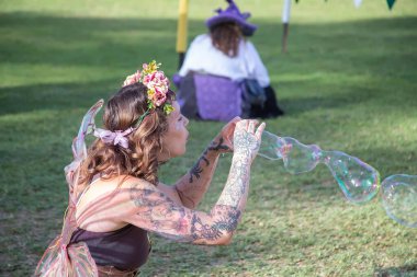 Paracombe, Güney Avustralya 05.03.2025. Güney Avustralya 'daki Ortaçağ Fuarı' nda yerel halk etkinliğinde düzenlenen canlı kostümlü festivalde peri sanatçısı baloncuklar patlatıyor..