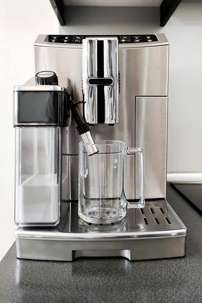 stock image Steel-colored coffee machine for making different types of coffee with glass cup on stand. Preparation for making coffee
