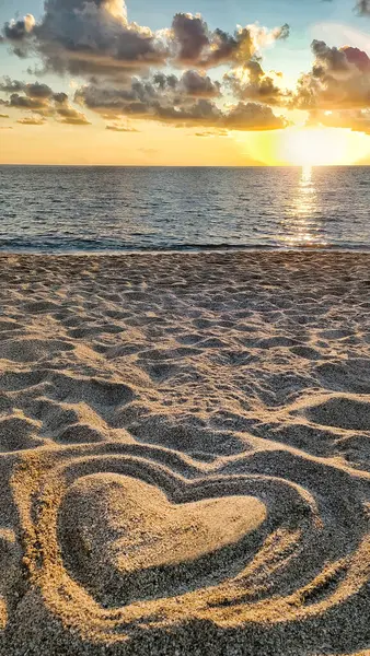 在沙滩上 在大海和美丽的夕阳的映衬下 用沙子做的心 在阳光下 爱与健康的概念 — 图库照片