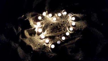 Heart made of small burning candles on sand in dark, concept of love and Valentines Day