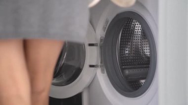 Kız bunu yıkamak için spor ayakkabılarını çamaşır makinesine koyuyor.