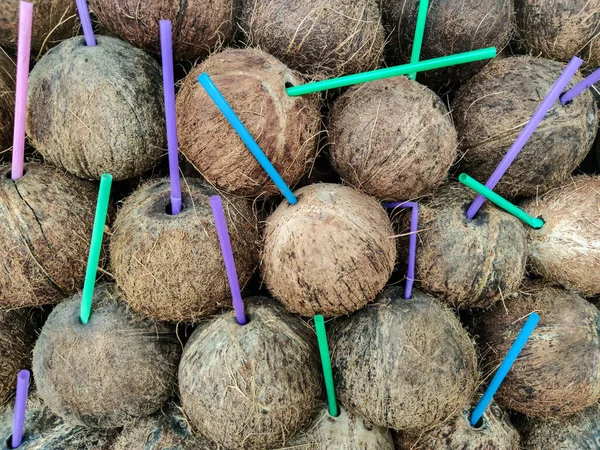 Renkli plastik kokteyl tüpleriyle hindistan cevizi arka planı.