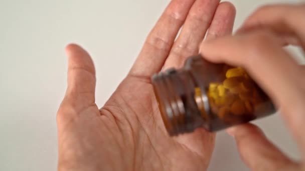 手握棕色药瓶的妇女的手 其中两片药丸被倒在她的手上 医学和健康的概念 — 图库视频影像