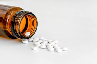 Dağıtılmış Beyaz Yuvarlak vitaminler ve Beyaz Arkaplanda Kahverengi Cam Şişe, Kopyalama Alanı, Yakın Çekim, Sağlık Konsepti.