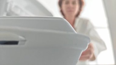 Orta yaşlı bir kadın tek kullanımlık yiyecek konteynırını buzdolabından alıyor..