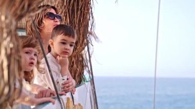 Küçük oğlu ve kızıyla birlikte yolcu gemisinde genç bir kadın. Onlar kıç tarafında duruyorlar, merakla denize bakıyorlar. Seyahat kavramı. Boşluğu kopyala