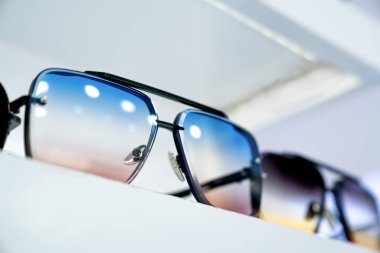 Ekranda gradyan lensleri olan şık güneş gözlüklerinin yakın çekimi, modern göz giysisi tasarımı, canlı renkleri yansıtan, parlak çerçeveler, moda ileri aksesuarları, perakende ortamında moda tarzını gösterme