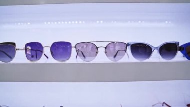 Düzenli güneş gözlüğü, modern gözlük tasarımları, çeşitli renkler ve şık aksesuarlar, perakende mağaza sunumunda sergilenen moda seçenekleri.