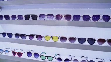 Beyaz raflarda canlı lens renkleri ve modaya uygun güneş gözlükleri, düzenli gözlük seçimi, moda perakende deneyimi ve alışveriş ortamının geliştirilmesi.