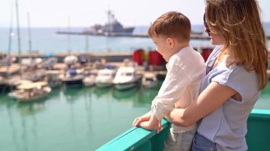 Küçük anne ve oğluyla gemiyle gezintiye çıkmak, deniz koyundan yelken açmak, güneşli bir yaz günü güvertede durmak, panoramanın tadını çıkarmak, aile gezisi konsepti..